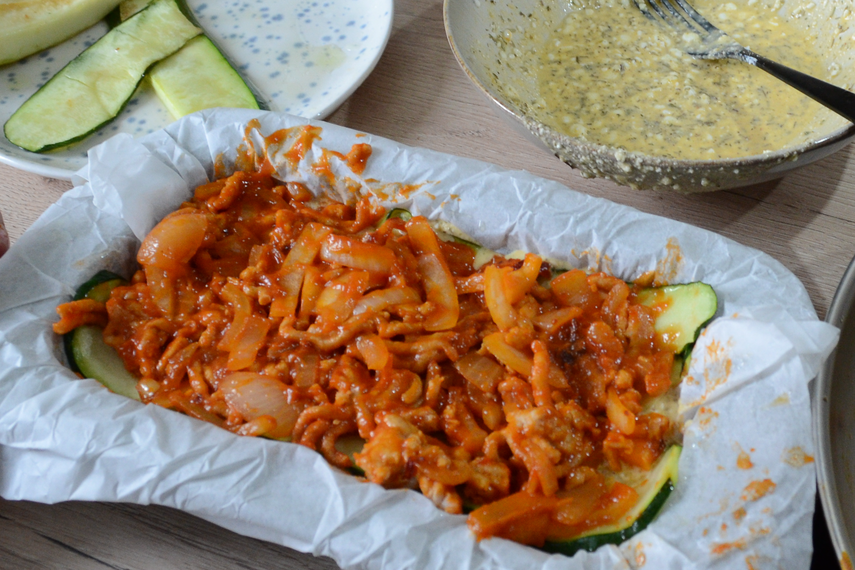 Baking dish filled with layers of cheese mixture and Zucchini 