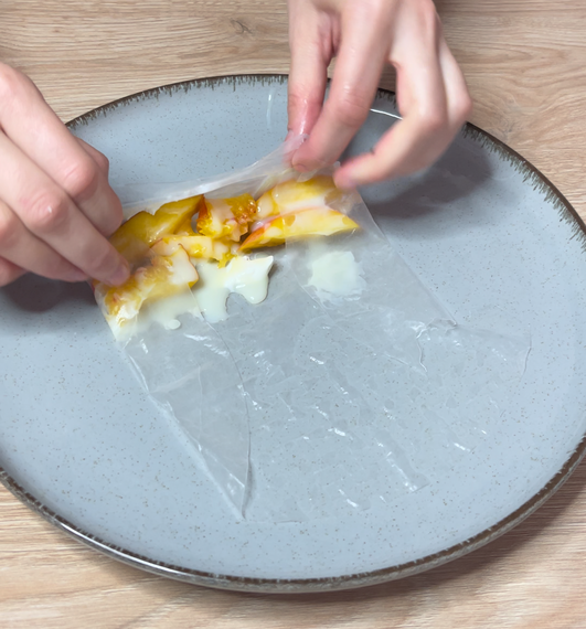 Rolling rice paper with peach and condensed milk inside