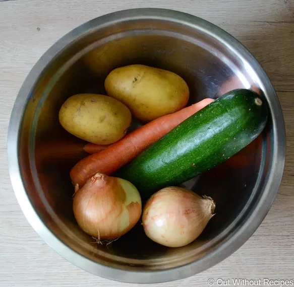 In a pot potato, onion, carrot, and zuccini 